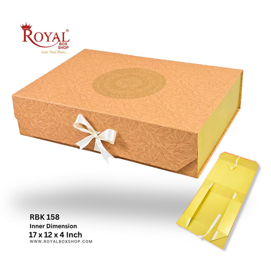 A gold-colored Royal Box Shop gift box with a white ribbon bow, shown alongside its yellow inner packaging and product specifications text on a white background.